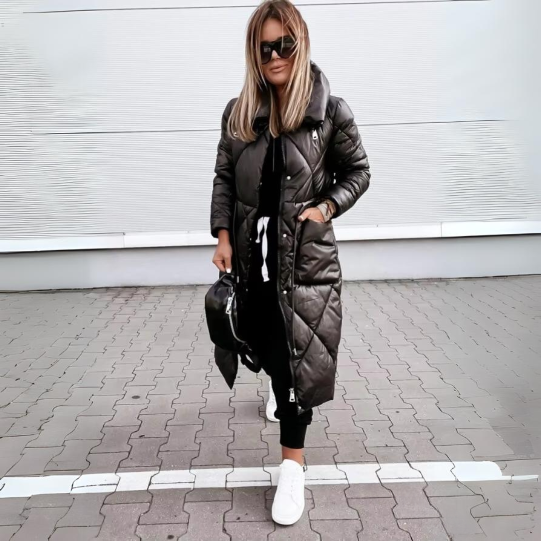 Modell fekete hosszú steppelt kabátban, zsebre tett kézzel, elölről.