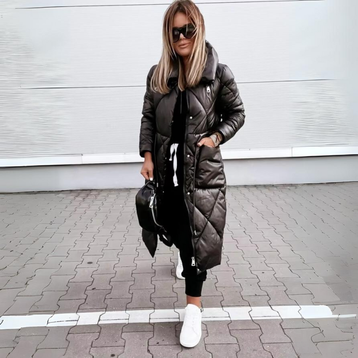 Modell fekete hosszú steppelt kabátban, zsebre tett kézzel, elölről.