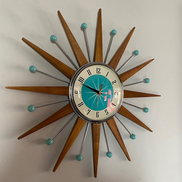 Kézzel készült, mid-century stílusú falióra fehér falon, enyhén oldalról fotózva.