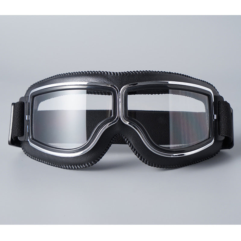 Fekete műbőr peremű szemüveg víztiszta lencsével, krómozott kerettel és állítható fekete pánttal, szürke háttér előtt. 16