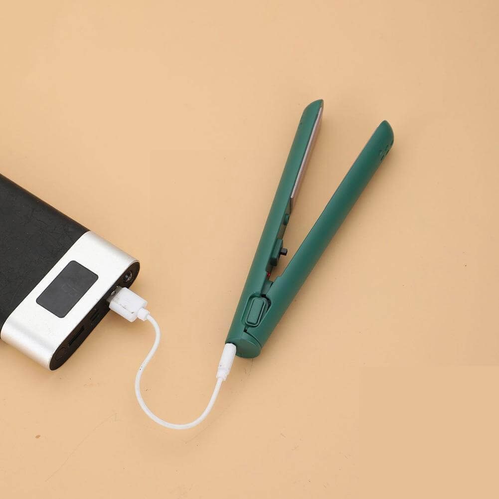 Zöld, kinyitott hajvasaló fehér USB-kábellel külső akkumulátorról töltve, barackszínű felületen. 11