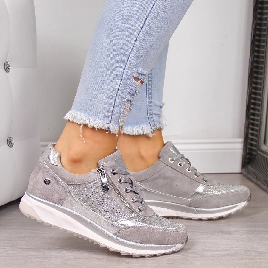 Szürke, ezüst díszítésű női sneaker viselve, oldalnézetből.