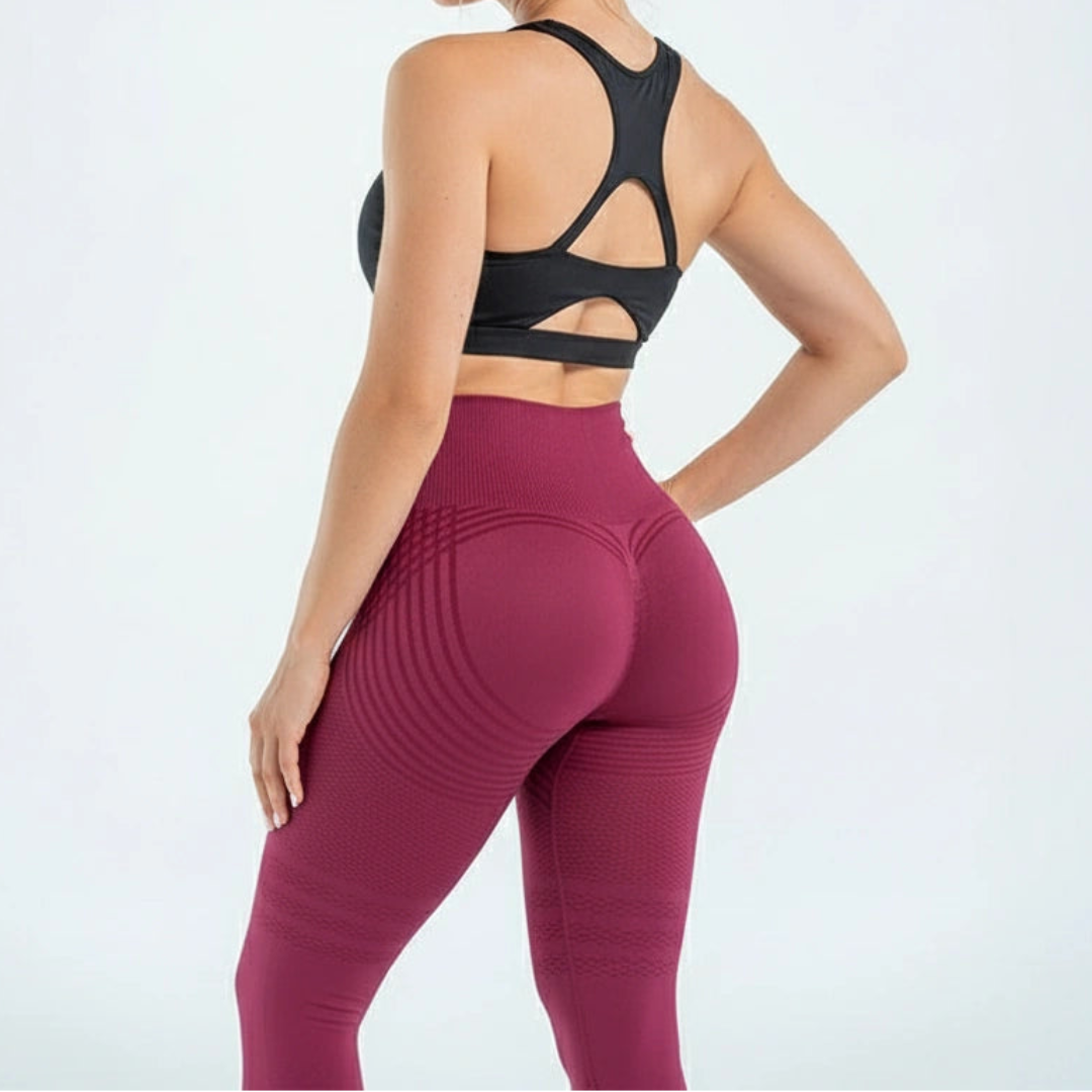Bordó leggings hátulról, fekete sportmelltartós modellen, a fenéken ívelő csíkokkal és formázó hátsó szabással. 6