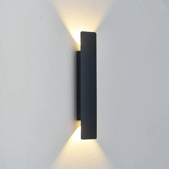Fekete Noir LED kültéri fali lámpa közeli képe világos falon, felfelé és lefelé világítva.
