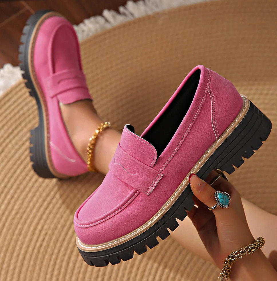 Rózsaszín loaferek, az egyiket kézben tartja a modell, a belső bélés és a platformtalp látszik.
