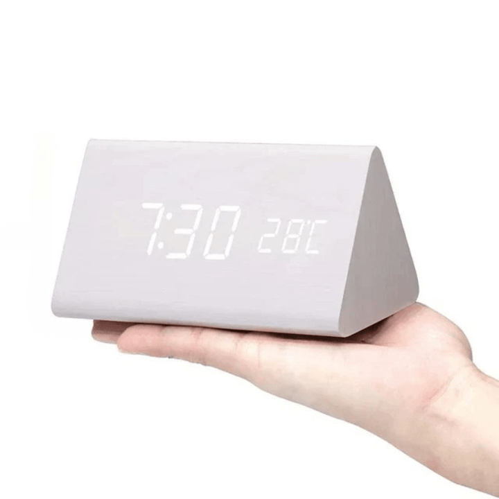 Fehér háromszög alakú LED faóra fehér LED-kijelzővel egy tenyéren.