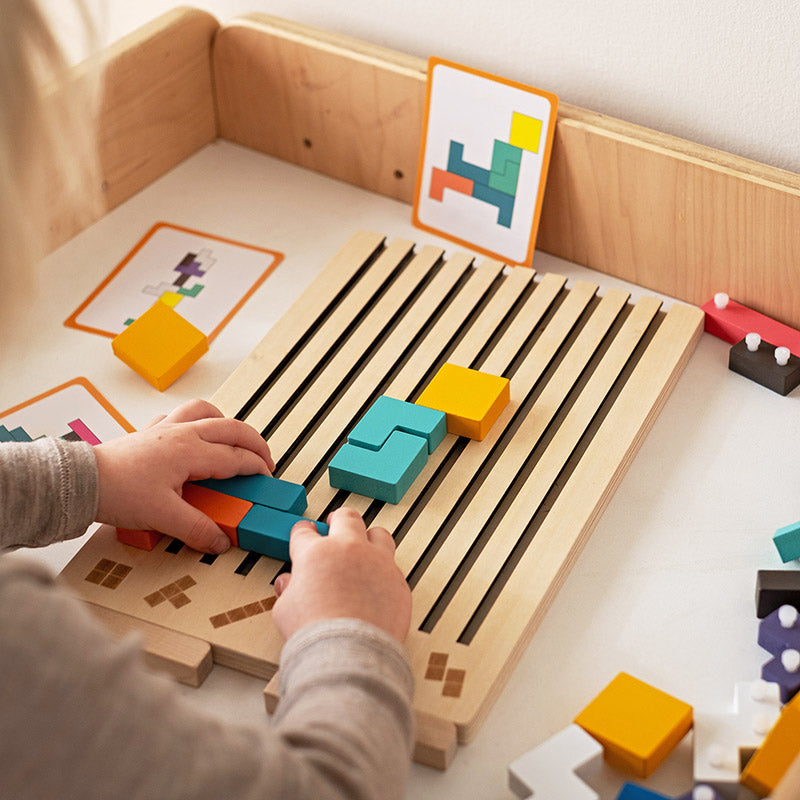 Fa Tetris puzzle játék, gyermek kezei színes elemeket helyeznek a táblára.