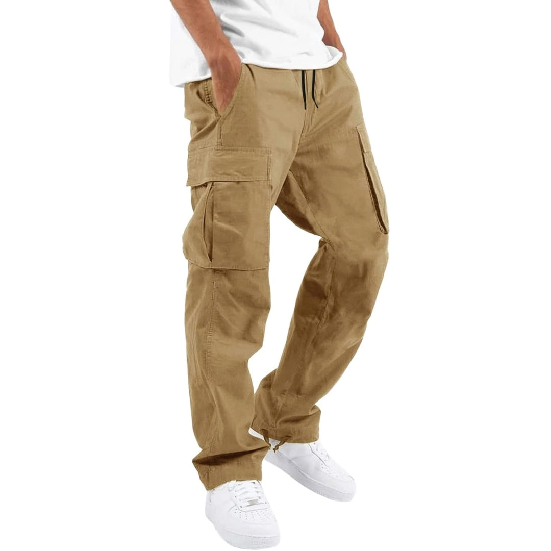 Világos khaki cargo nadrág oldalnézetből, modellen fehér pólóval és fehér cipővel, kezek a zsebekben.