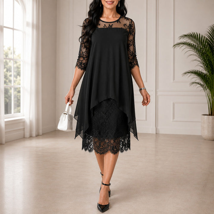 Fekete változat, a modell fehér kézitáskával áll: csipkés vállrész és ujjak, aszimmetrikus sifon felsőréteg, csipke szegélyű alsó szoknya.