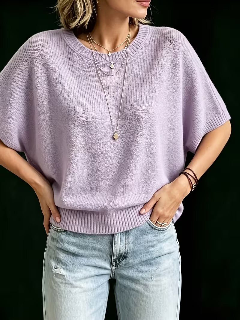 Orgonalila kötött felső elölről, modellen, kezét csípőjére téve, a bordázott szegély és farmer látszik.