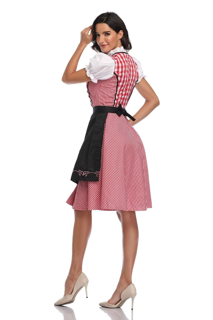 Piros-fehér kockás női dirndl hátulnézetben fekete masnis kötővel és fekete hímzett köténnyel.