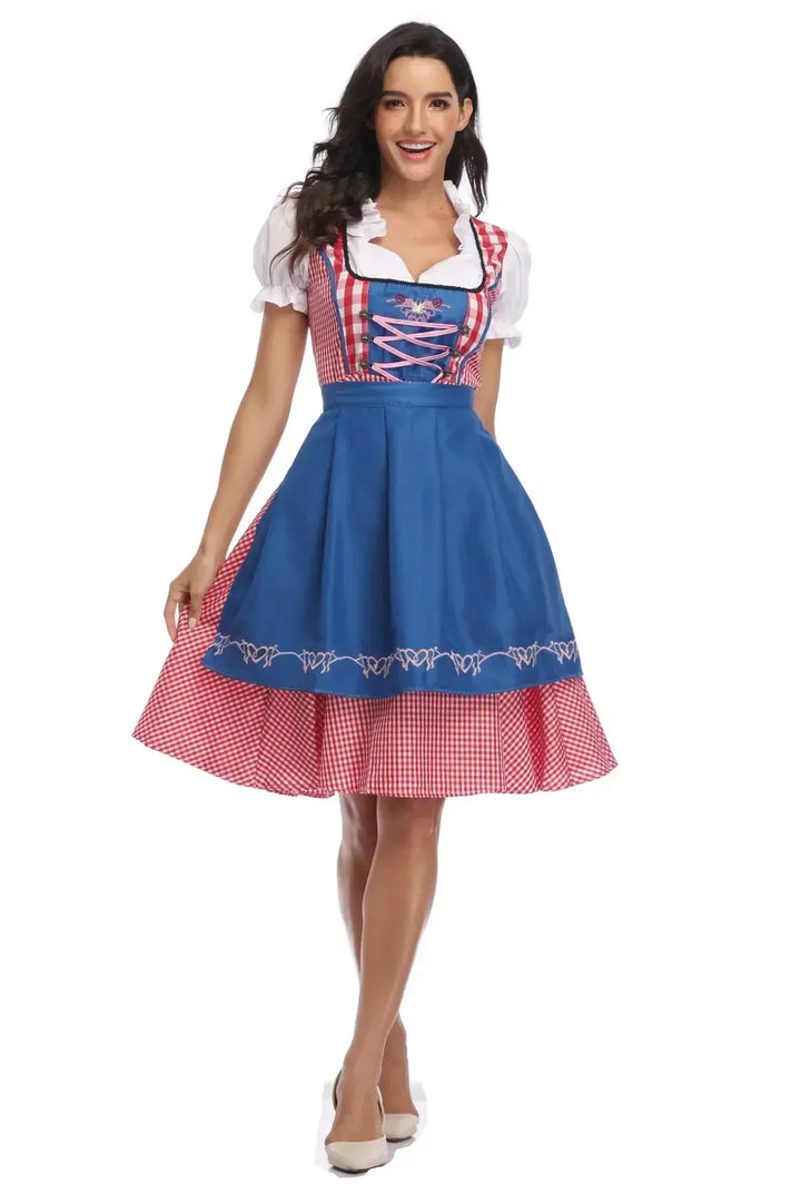 Piros kockás női dirndl élénkkék hímzett köténnyel és rózsaszín fűzővel, elölnézetben.