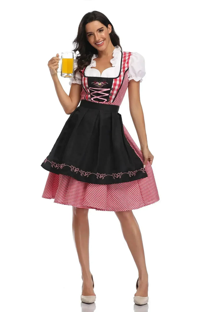 Piros kockás női dirndl fekete hímzett köténnyel és rózsaszín fűzővel.
