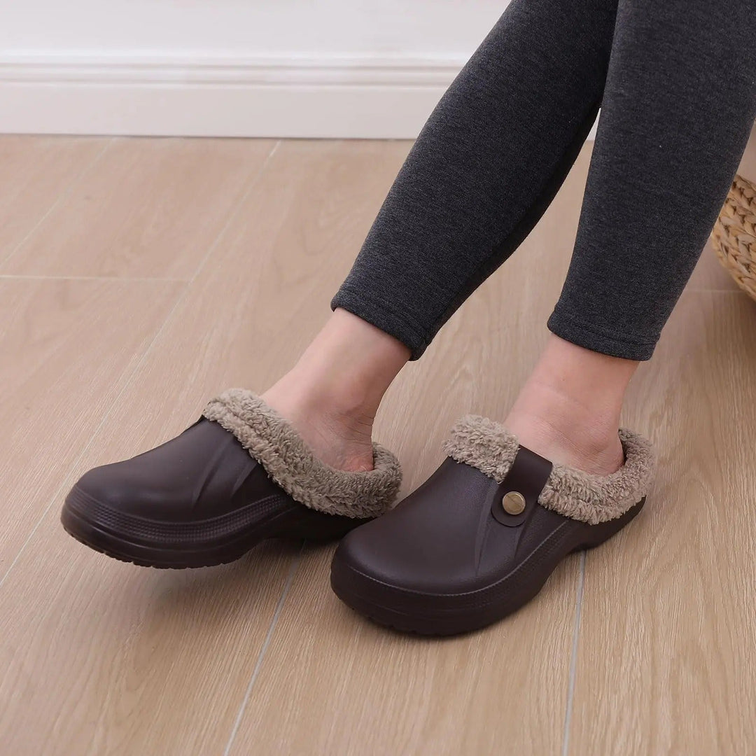Barna klumpa viselés közben egy sötétszürke leggingset viselő lábán, világos faburkolatú padlón. 7