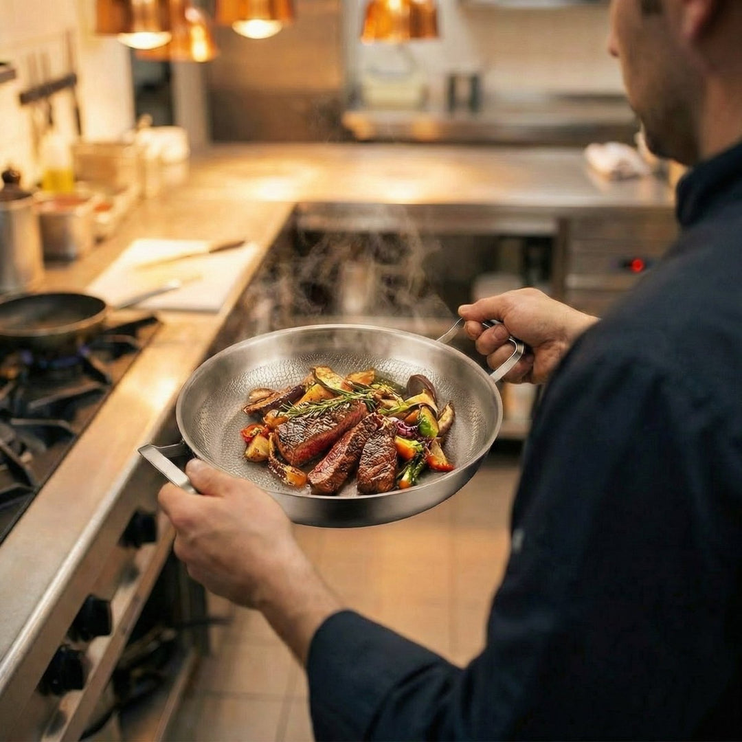 Szakács két kézzel tartja a két fogantyúnál fogva a serpenyőt, amelyben steakszeletek és sült zöldségek gőzölögnek egy konyhában. 6