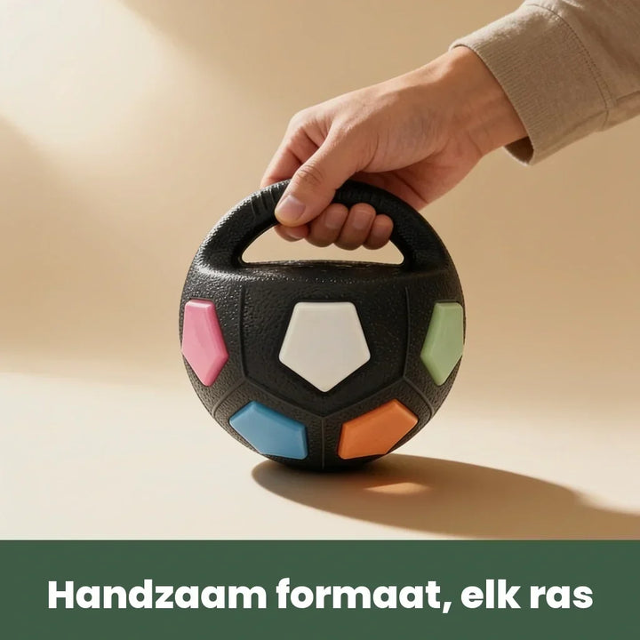 Egy kéz a fogantyúnál fogva tartja a fekete labdát, amelyen színes betétek láthatók, így érzékelhető a kényelmes méret.